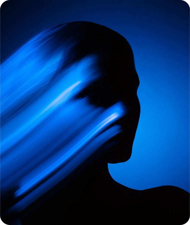 A profile in silhouette streaked with blue motion light